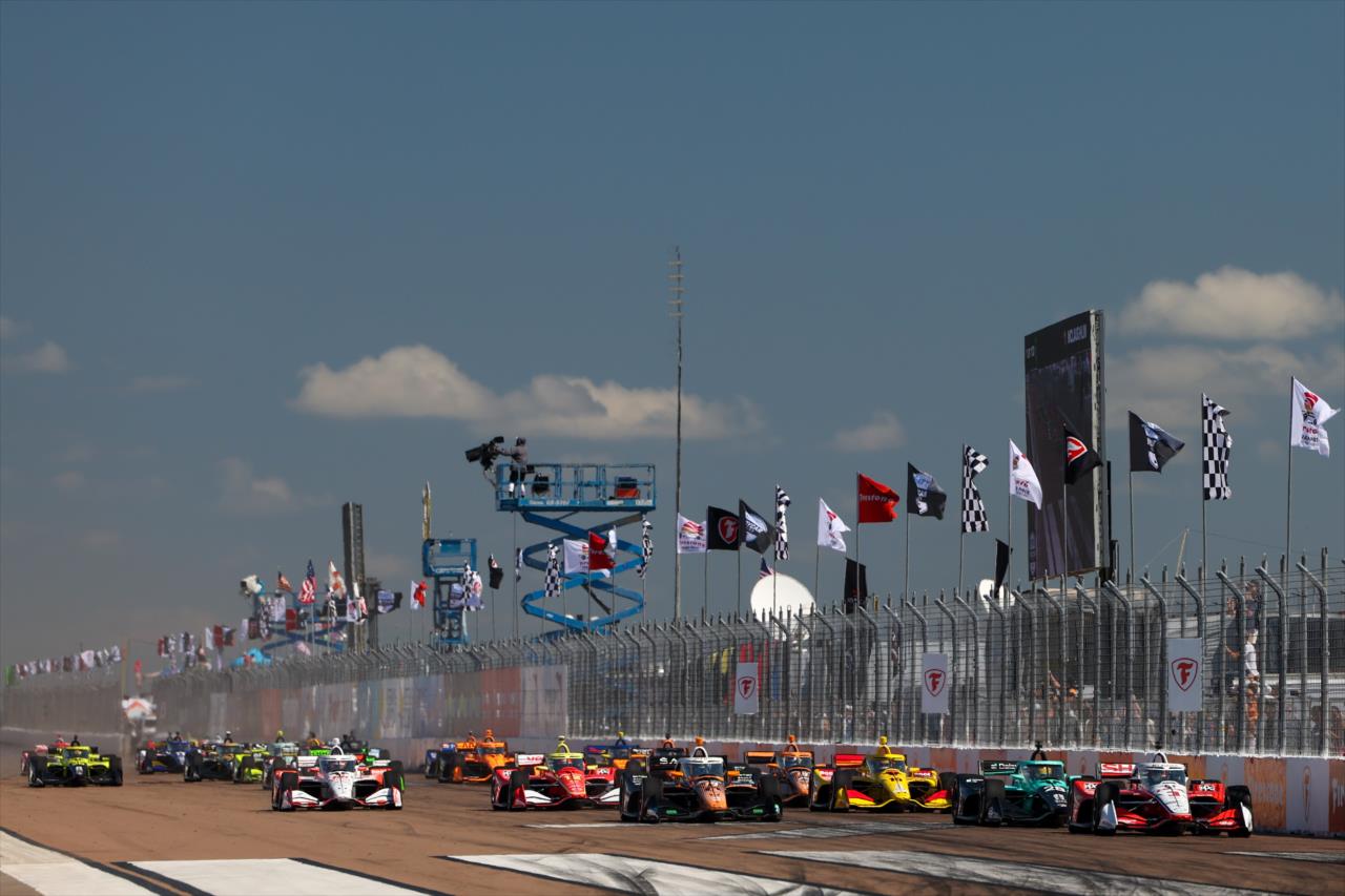 Vista panorámica del pelotón acelerando hacia Curva 1 en circuito urbano